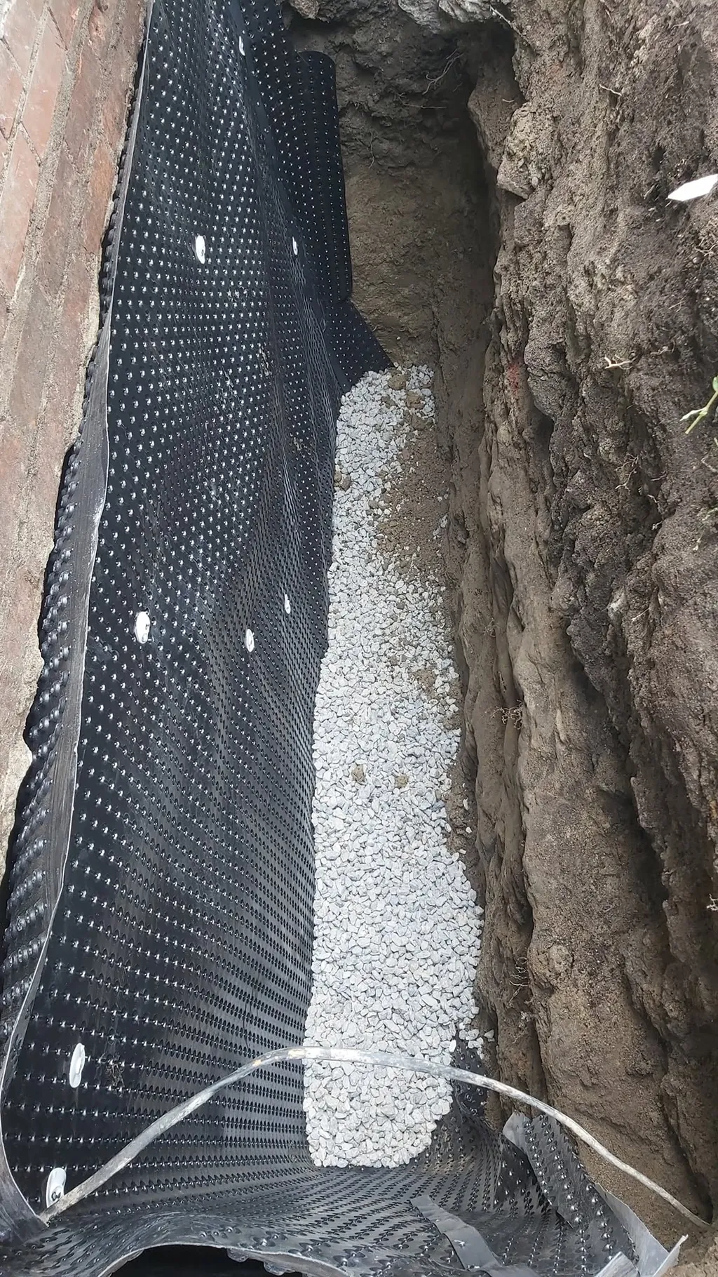 Géocomposite drainant contre la paroi d’une tranchée remplie de gravier